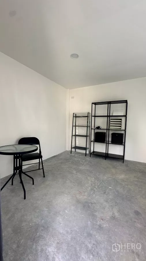 บ้าน ให้เช่าหรือขายในKhlong Toei, Bangkok - ห้องอเนกประสงค์ พื้นคอนกรีต ชั้นวางโลหะ และโต๊ะกลมขนาดเล็ก.