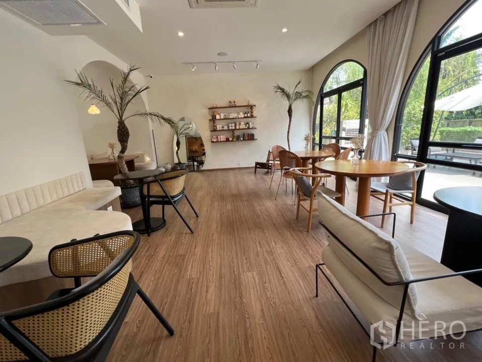 零售空间 出租在Watthana, Bangkok - 宽敞房间设长条卡座、圆桌、装饰棕榈与大幅拱形窗。