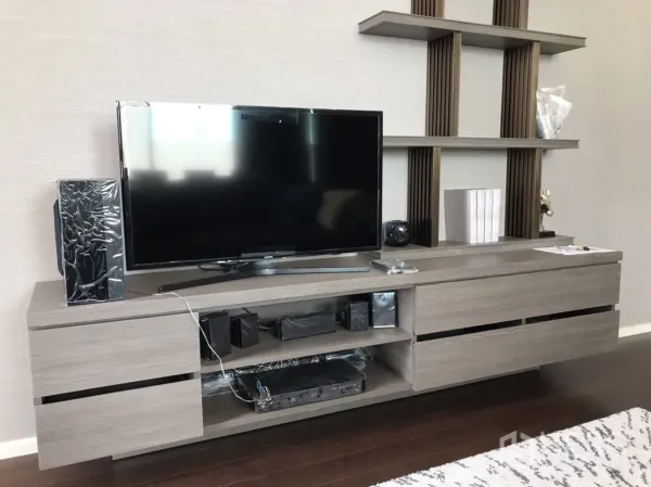 Condominium for rent or sale in Huai Khwang, Bangkok - Contemporary living area with built-in TV console and open display shelves.