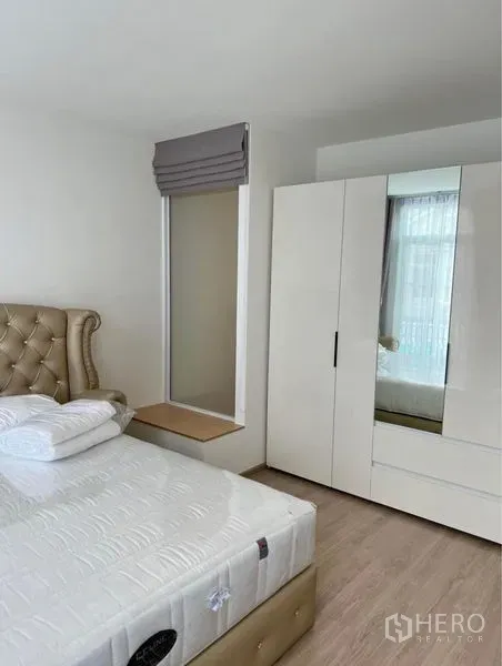 联排别墅 出租在Prawet, Bangkok - 温馨卧室，软包床、高挑窄窗配百褶帘，以及白色衣柜。