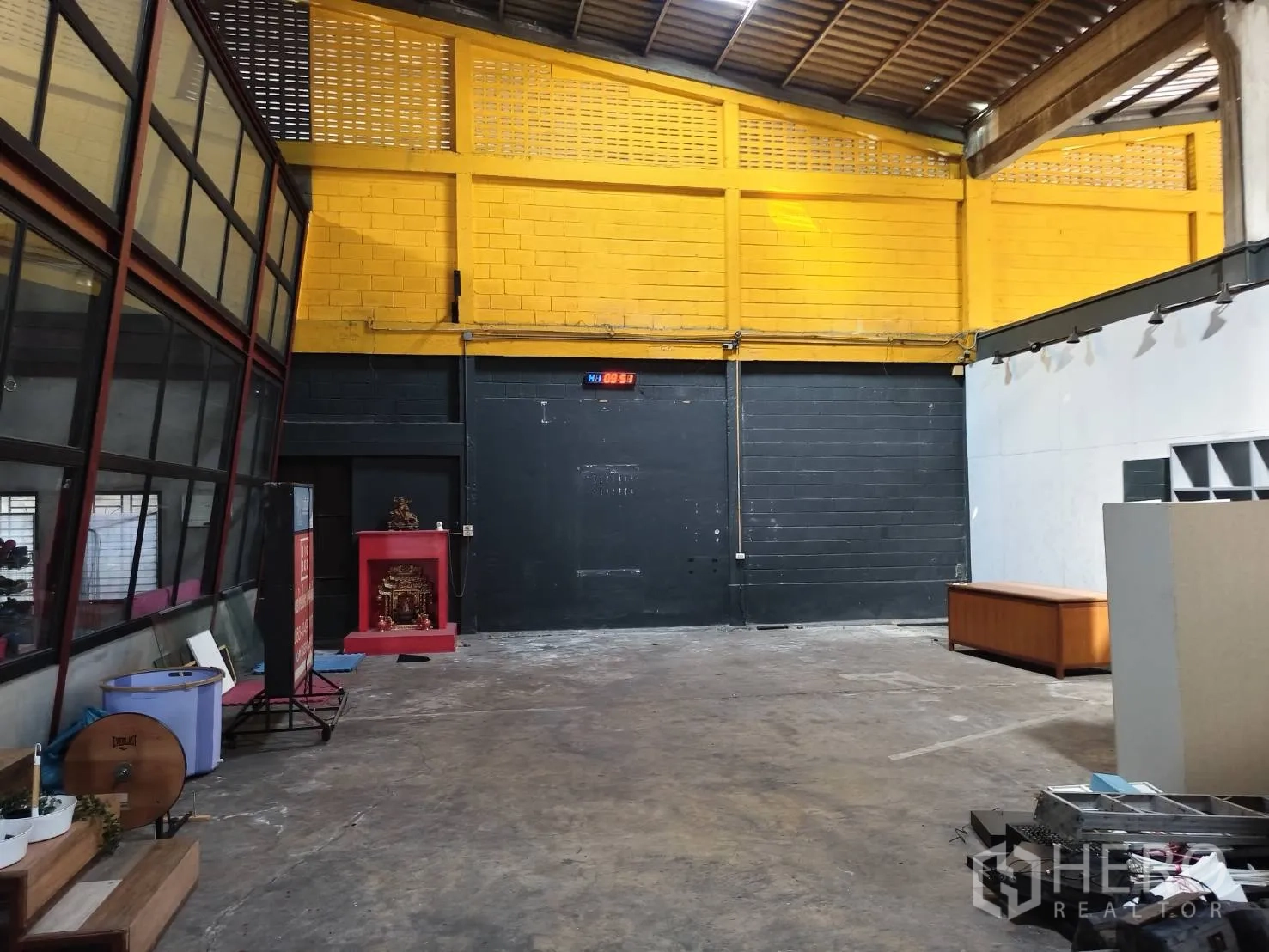คลังสินค้า ให้เช่าในKhlong Toei, Bangkok - ผนังสีเหลืองสด ประตูม้วนสีดำ และพื้นที่โกดังโล่ง