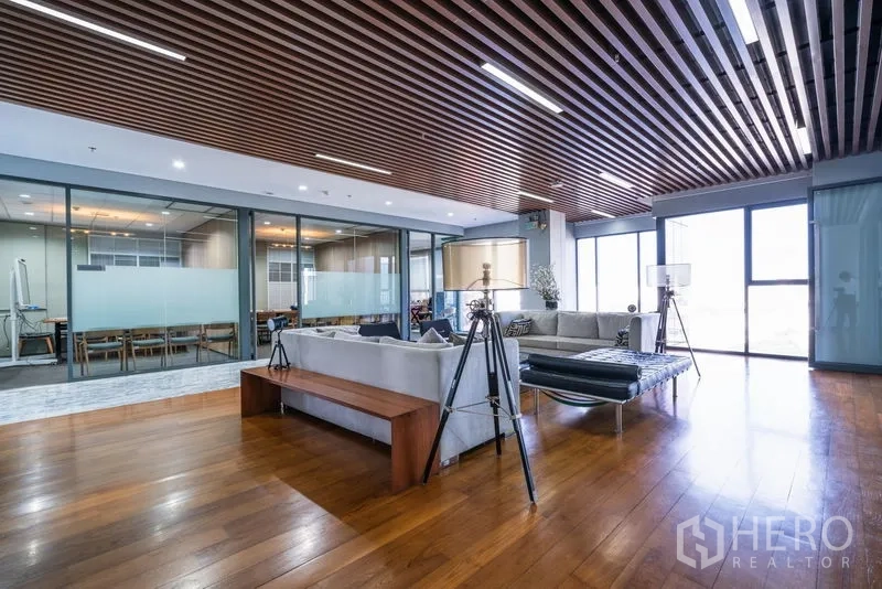 Office Space for rent - Spacious lounge with sofas, wood ceiling slats, and floor-to-ceiling windows.