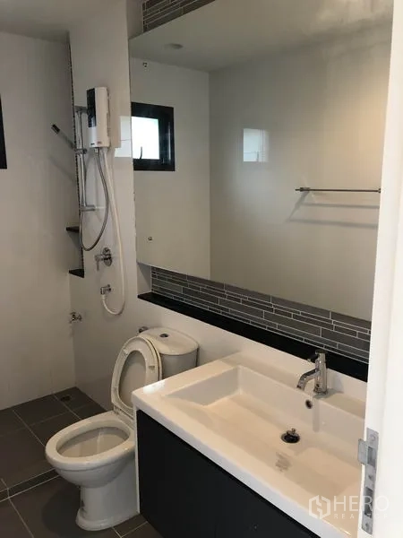 Detached House for rent or sale in Bang Kapi, Bangkok - Second bathroom with large mirror, vanity basin and shower set.