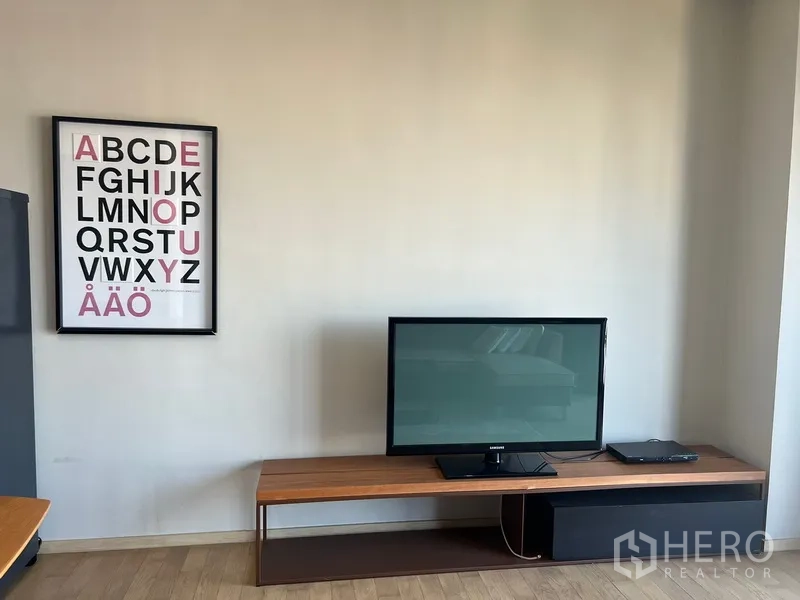 Condominium for rent or sale in Watthana, Bangkok - TV on a low console with typography artwork on a neutral wall in the living area
