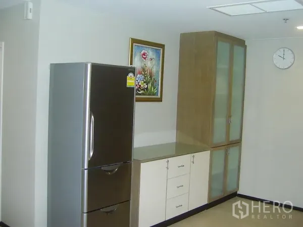 คอนโด ให้เช่าในKhlong Toei, Bangkok - มุมครัวพร้อมตู้เย็นสแตนเลสและตู้บิวท์อินบานกระจกฝ้า พร้อมกรอบรูปติดผนัง