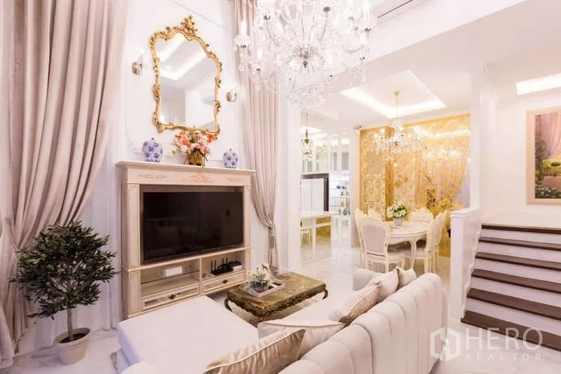 联排别墅 出租在Lat Phrao, Bangkok - 优雅客餐厅，水晶吊灯、电视柜、窗帘与侧边楼梯。