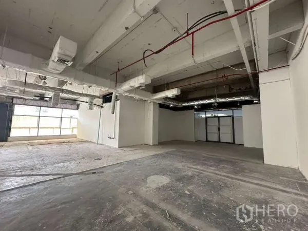 办公空间 出租 - 宽敞未装修办公室，混凝土地面、整面采光窗与管道空调系统。