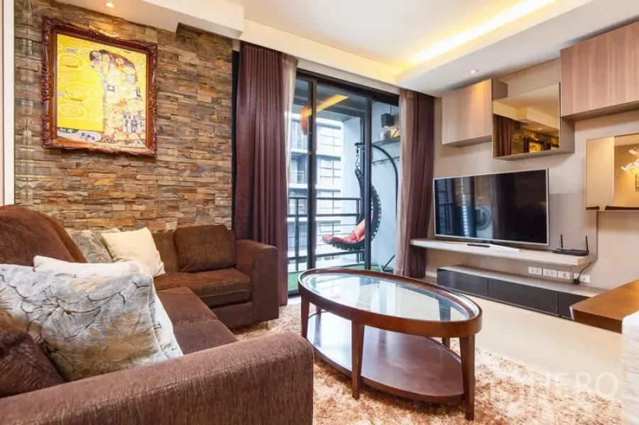 公寓 出租在Watthana, Bangkok - 电视媒体墙与嵌入式收纳，推拉门通往阳台，设有吊椅。