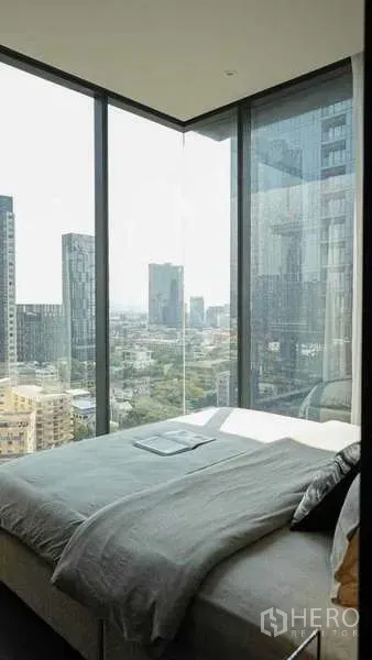 Condominium for rent or sale in Watthana, Bangkok - Corner bedroom with floor-to-ceiling glass offering panoramic Bangkok skyline views.