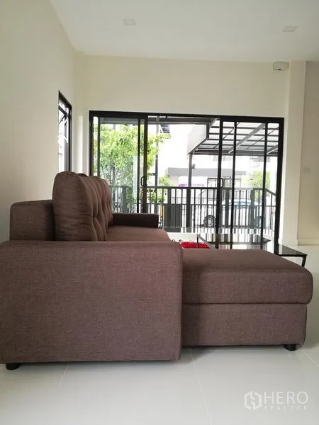 Townhouse for rent in Saphan Sung, Bangkok - Open-plan lounge with sofa next to large sliding doors and covered porch.