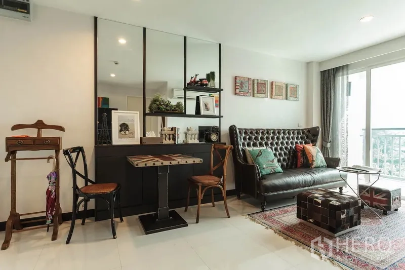 公寓 出租在Khlong Toei, Bangkok - 舒适客厅，纽扣皮沙发、镜面墙，推拉门通向阳台。