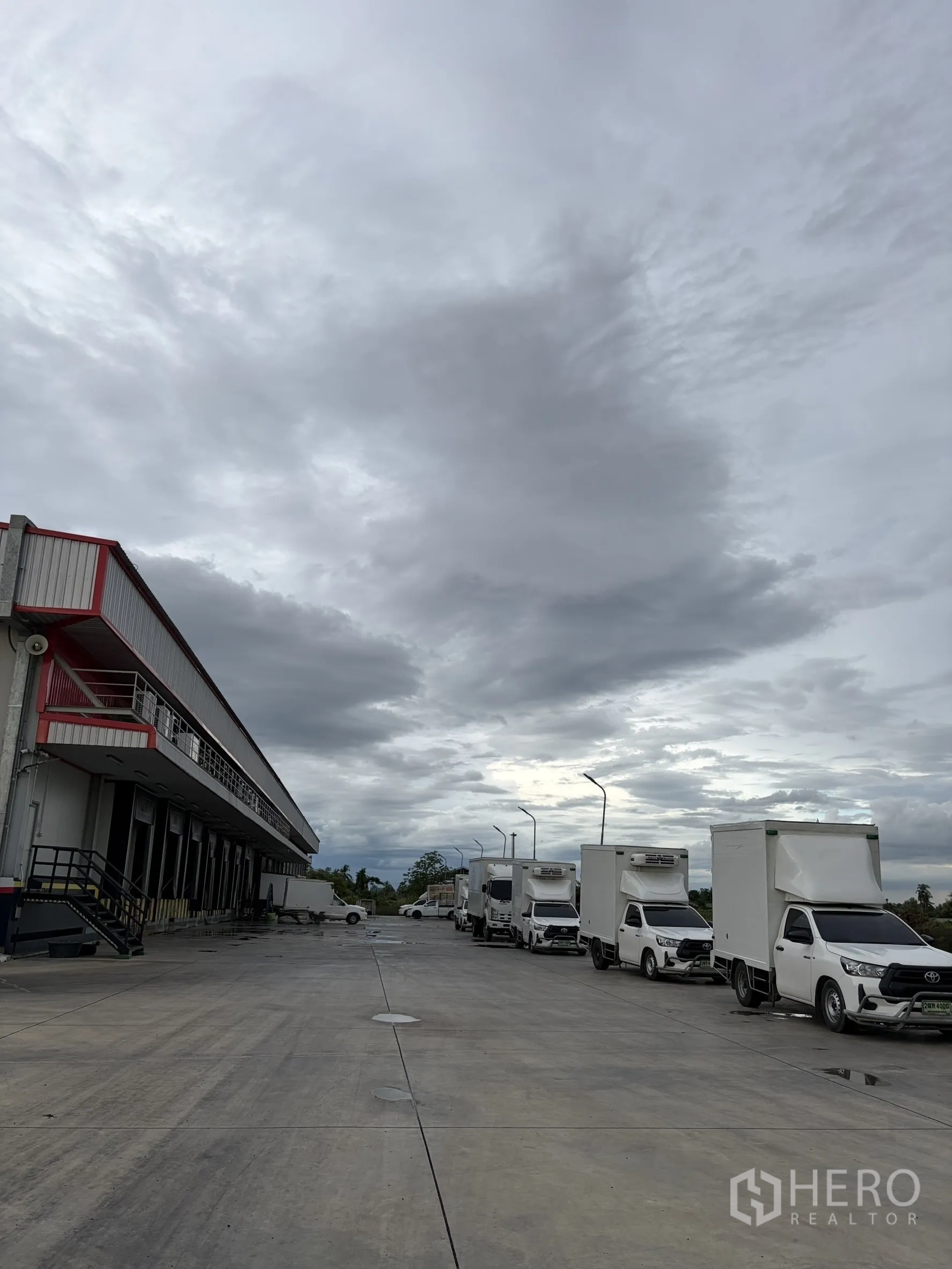 Factory for sale in Mueang Nakhon Pathom, Nakhon Pathom - Line of refrigerated delivery trucks parked on expansive yard.