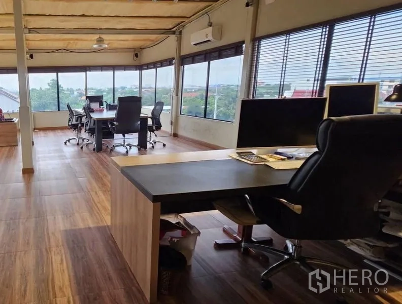 Warehouse for rent in Bang Kruai, Nonthaburi - Open-plan office with desks, wide windows and laminate floors overlooking greenery.
