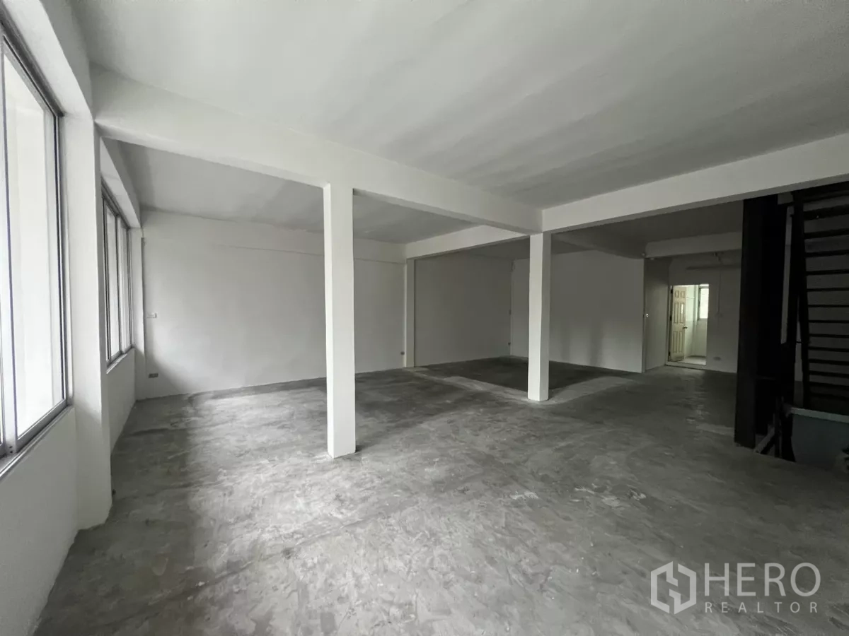 店屋 出租在Watthana, Bangkok - 大开间室内空间，设立柱、窗户与通往楼上的楼梯。