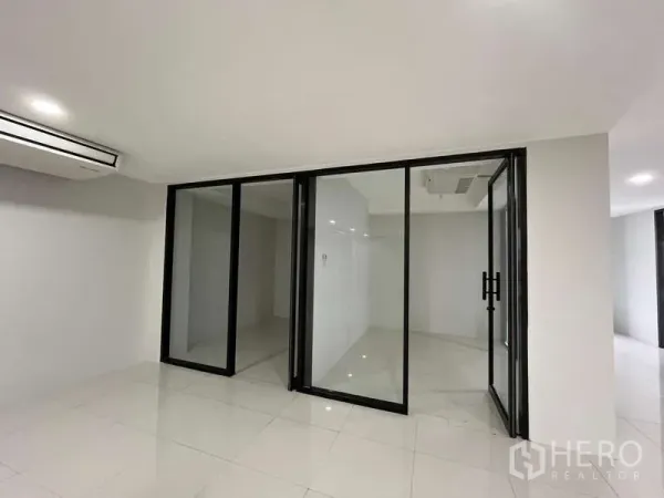 Office Space for rent in Prawet, Bangkok - Bright Bangkok office room with glass partition walls, black aluminum frames, white tiles and ceiling air-conditioning.