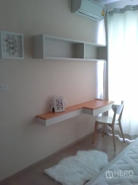 Condominium for rent or sale in Watthana, Bangkok - Bedroom study nook featuring a floating desk, open shelves, window and sheer curtains.