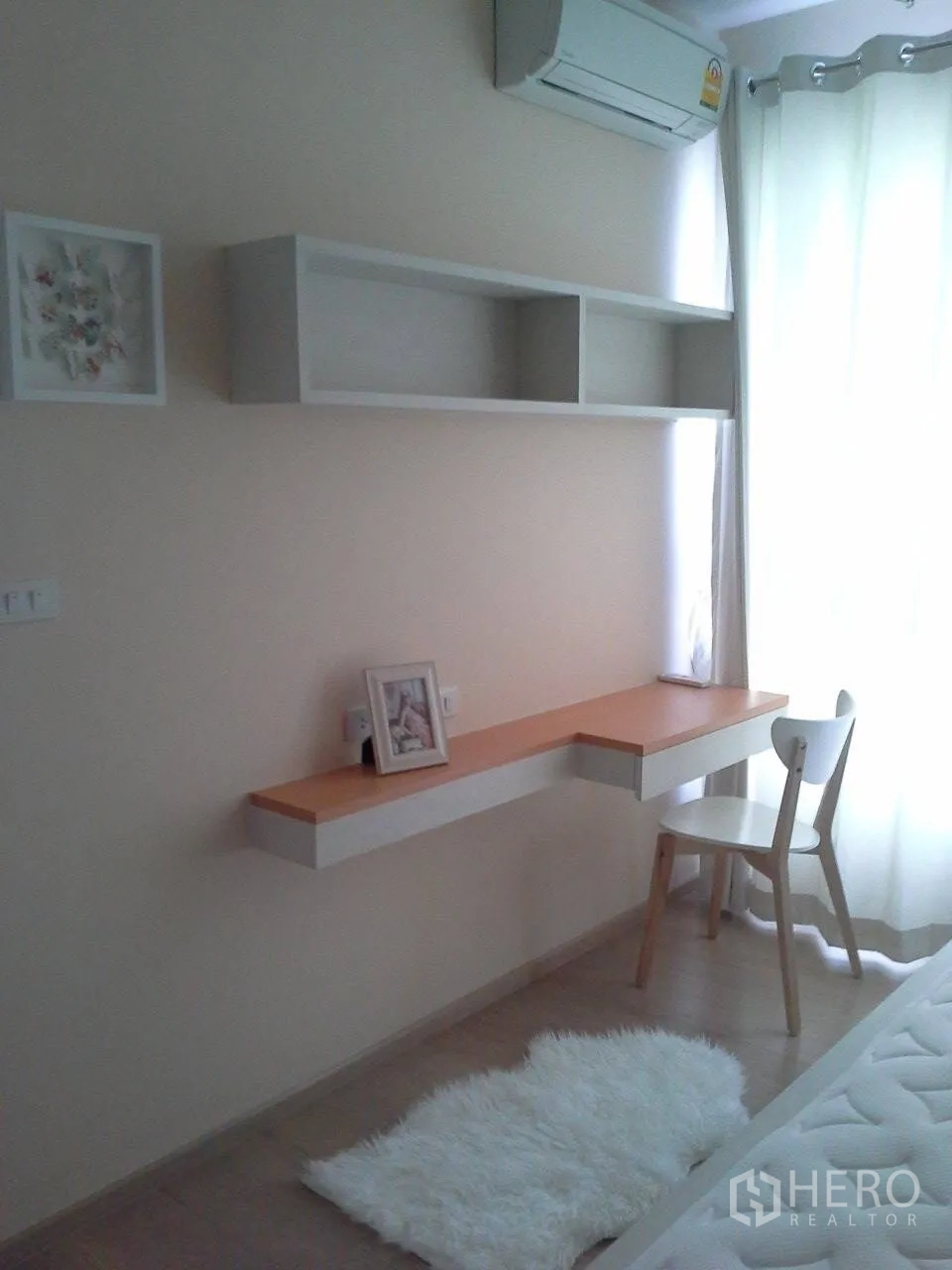Condominium for rent or sale in Watthana, Bangkok - Bedroom study nook featuring a floating desk, open shelves, window and sheer curtains.