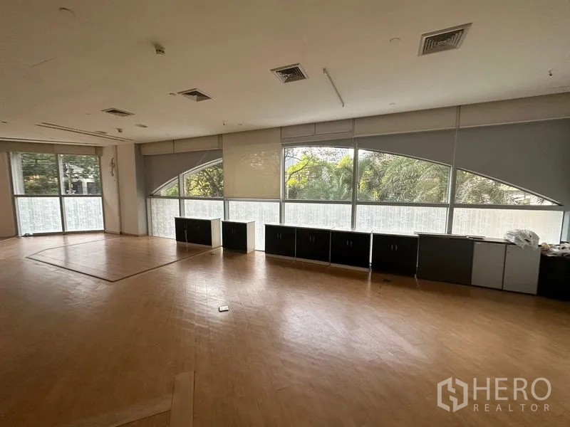 办公空间 出租在Pathum Wan, Bangkok - 宽阔办公区域，环景窗配百叶帘与内置储物柜，面向绿景。