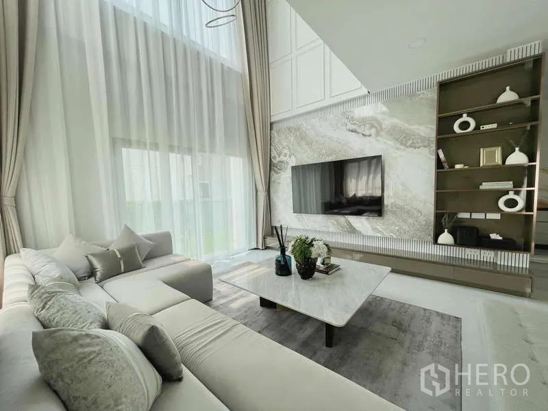 Detached House for rent in Bang Phli, Samut Prakan - Contemporary living area with L-shaped sofa, marble coffee table and display shelving.