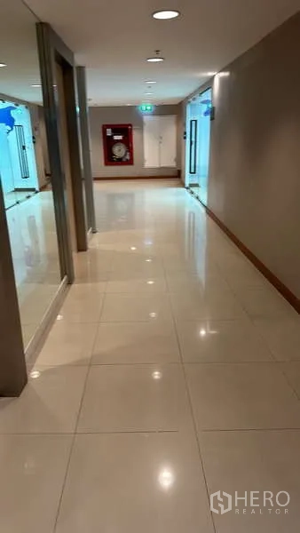 สำนักงาน ให้เช่า - โถงทางเดินอาคารสว่าง พื้นกระเบื้องเงา หน้าห้องกระจก และตู้สายฉีดดับเพลิงท้ายทางเดิน