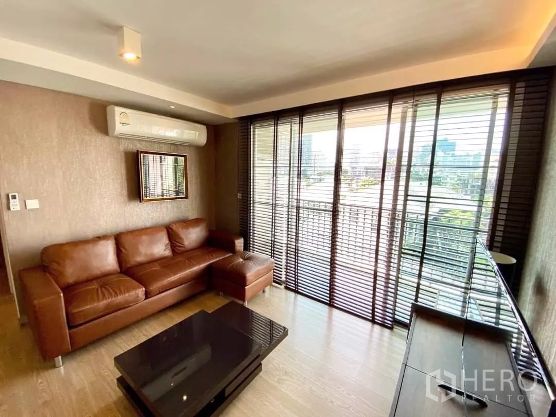 คอนโด ให้เช่าในWatthana, Bangkok - มุมนั่งเล่นโซฟาหนังสีน้ำตาล มองออกสู่ระเบียงและทีวี