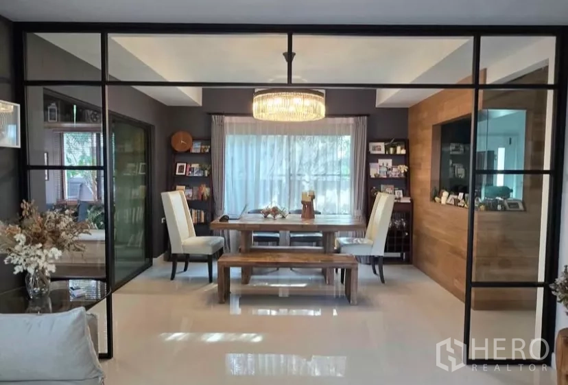 独立式住宅 出租在Bang Phli, Samut Prakan - 玻璃隔断后的餐厅，水晶吊灯与木质餐桌