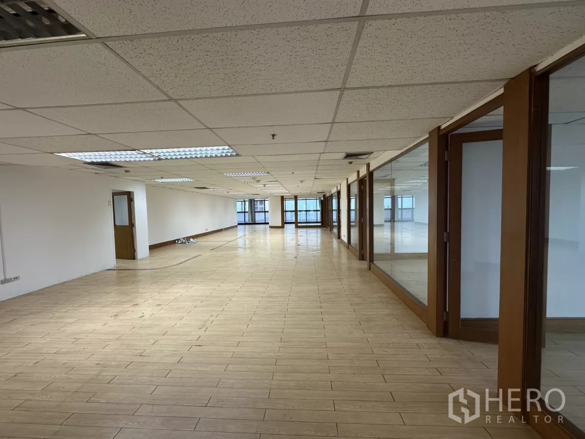 Office Space for rent in Watthana, Bangkok - Open corridor-style office area with glass offices to the right and windows at both ends.