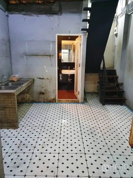 อาคารพาณิชย์ ให้เช่าหรือขายในKhlong Toei, Bangkok - พื้นที่ชั้นล่างปูพื้นลายตาราง มีซิงก์ปูน ประตูห้องน้ำเปิด และบันไดขึ้นชั้นบนในอาคารพาณิชย์