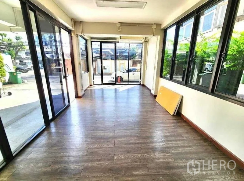 Office Space for rent or sale in Din Daeng, Bangkok - Ground-floor glass-fronted room with wood-look flooring and sliding doors.