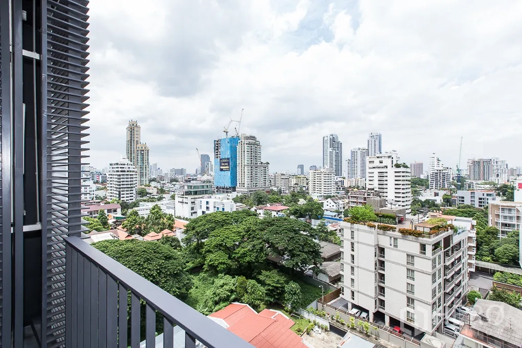 Condominium for rent in Watthana, Bangkok - Balcony with privacy louvers overlooking green treetops and Bangkok skyline.