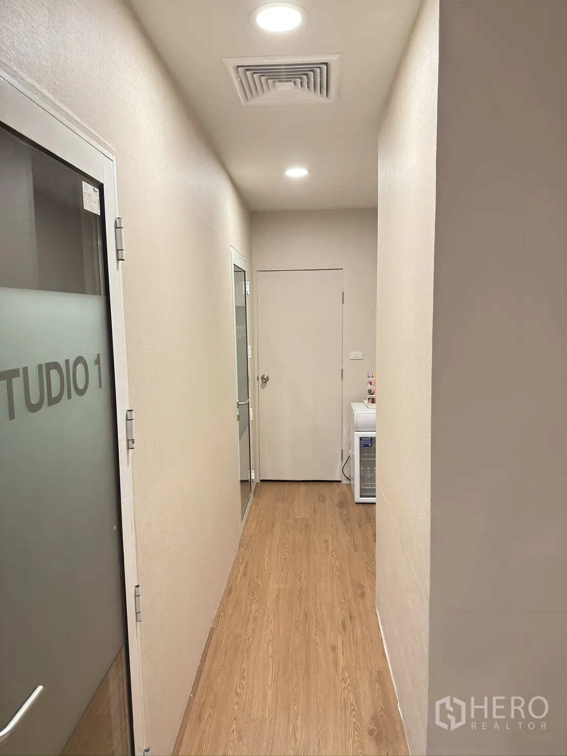 Retail Space for rent in Khlong Toei, Bangkok - Hallway with frosted glass studio door, ceiling spotlights, and wood-look flooring.