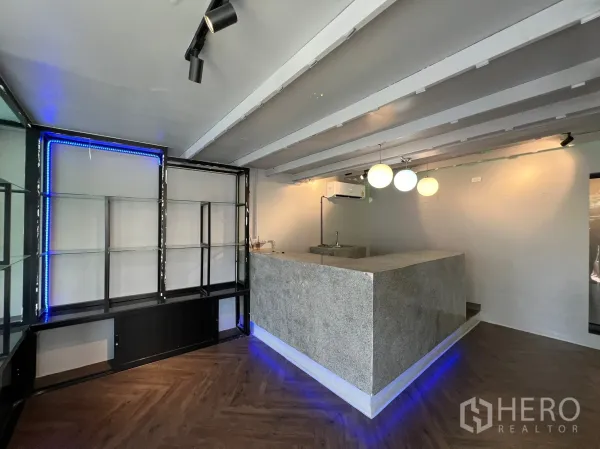 零售空间 出租在Watthana, Bangkok - 零售区配石材服务吧台、吊灯与金属玻璃展示架，带蓝色LED灯带