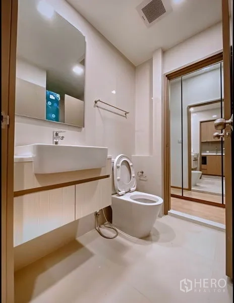 Condominium for sale in Chatuchak, Bangkok - Clean bathroom with vanity, toilet and sliding door to bedroom closet.