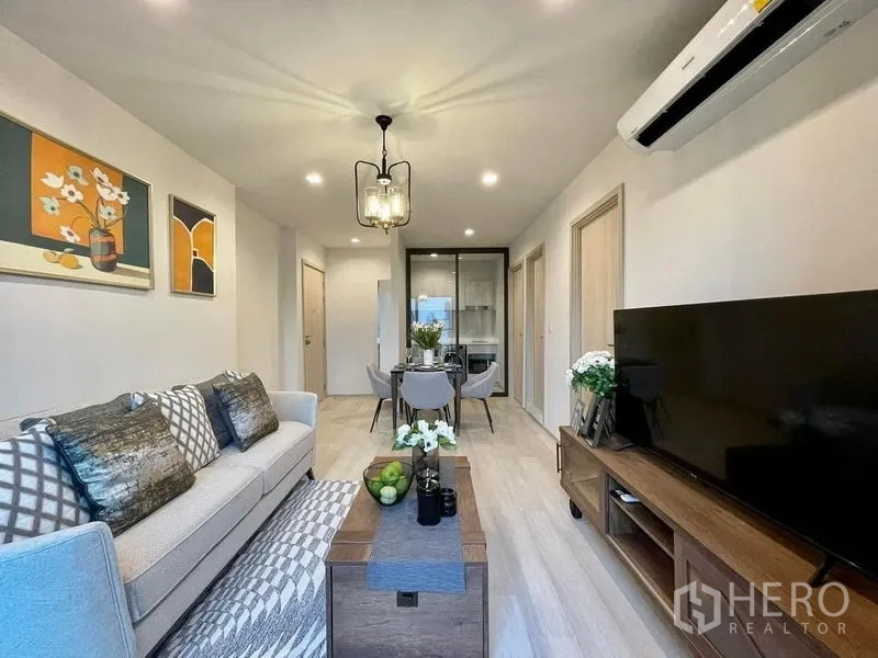 Condominium for rent in Pathum Wan, Bangkok - Open-plan living and dining area with wood flooring, pendant light and glass-partition kitchen.