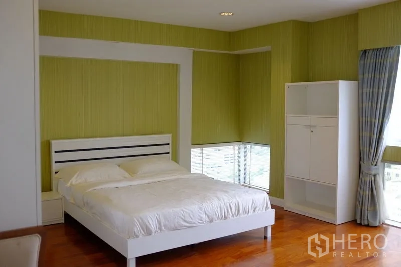 公寓 出租在Watthana, Bangkok - 宽敞卧室，绿色点缀墙、白色床与环幕窗。