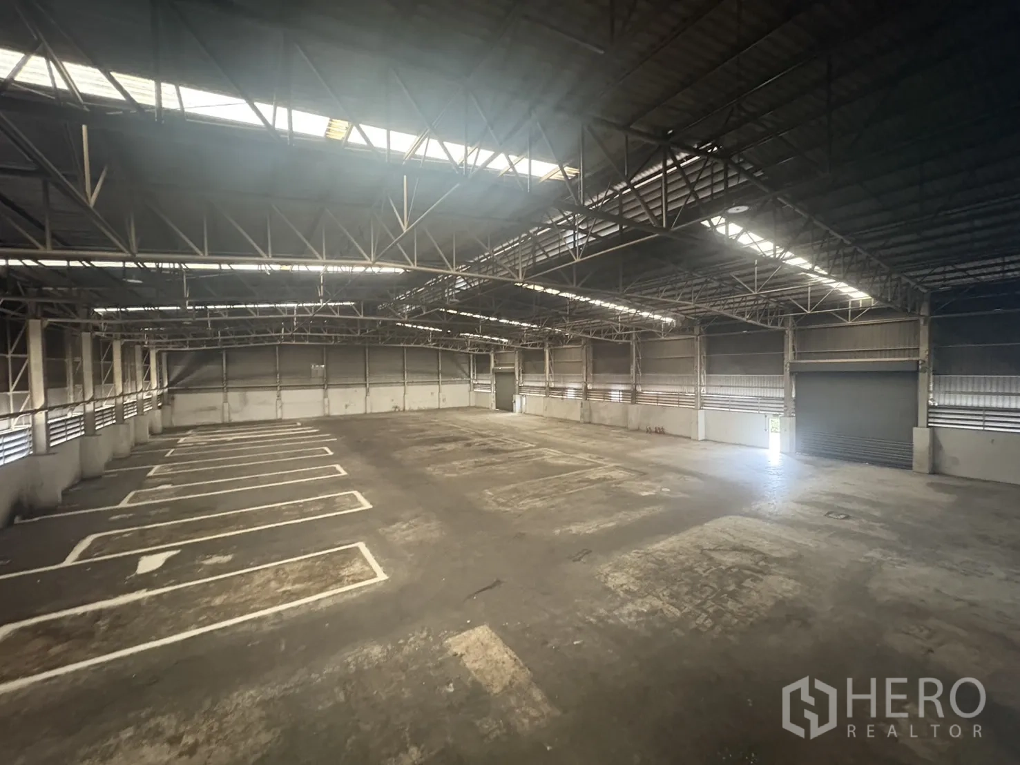 Factory for rent or sale in Samut Prakan - Ceiling trusses and long strip skylights inside the factory hall.