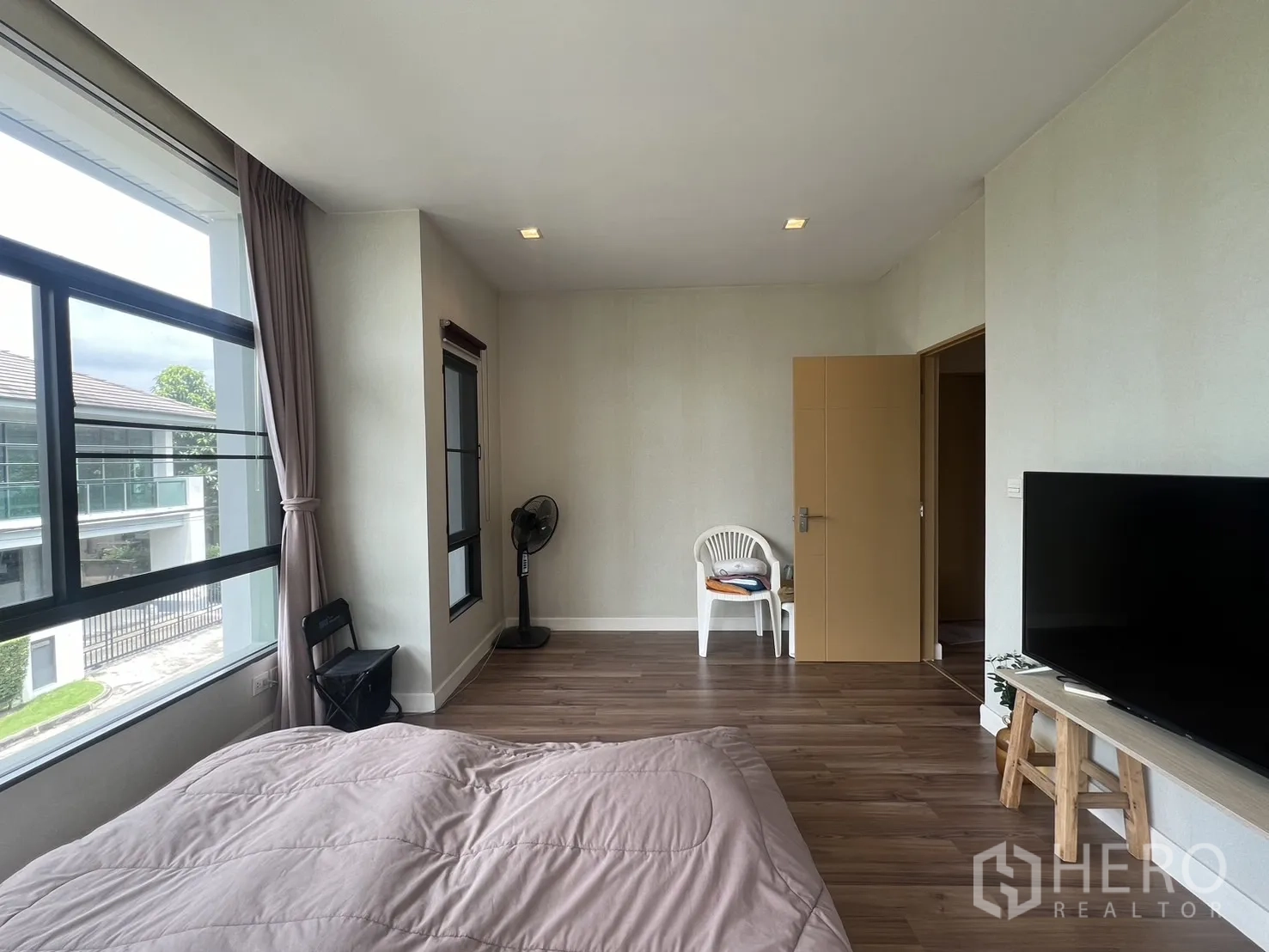 Detached House for rent in Bang Kapi, Bangkok - Bedroom corner with wide glazing and bed on laminate flooring.