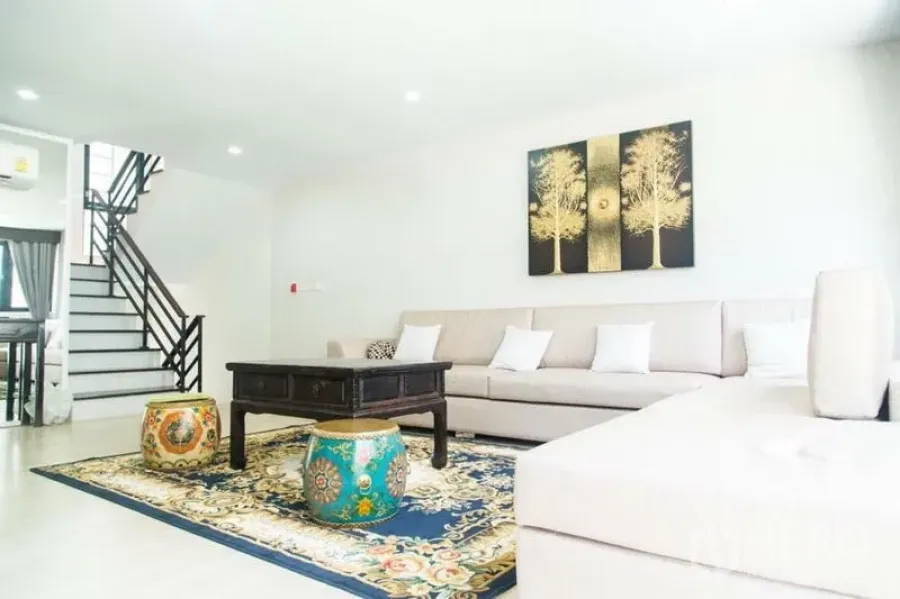 ทาวน์เฮาส์ ให้เช่าในYan Nawa, Bangkok - ห้องนั่งเล่นทาวน์เฮ้าส์สว่าง โซฟา L รูป พรมลาย โต๊ะกลางไม้ และบันไดเปิดโล่ง