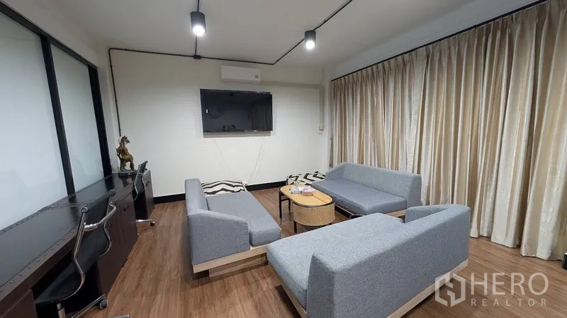 带办公室的家 出租或出售在Phra Khanong, Bangkok - 工作休闲区，办公椅、壁挂电视与灰色沙发。