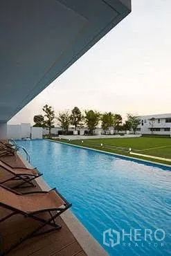 独栋房屋 for rent in Saphan Sung, Bangkok - 社区长形游泳池，旁有躺椅与草坪。