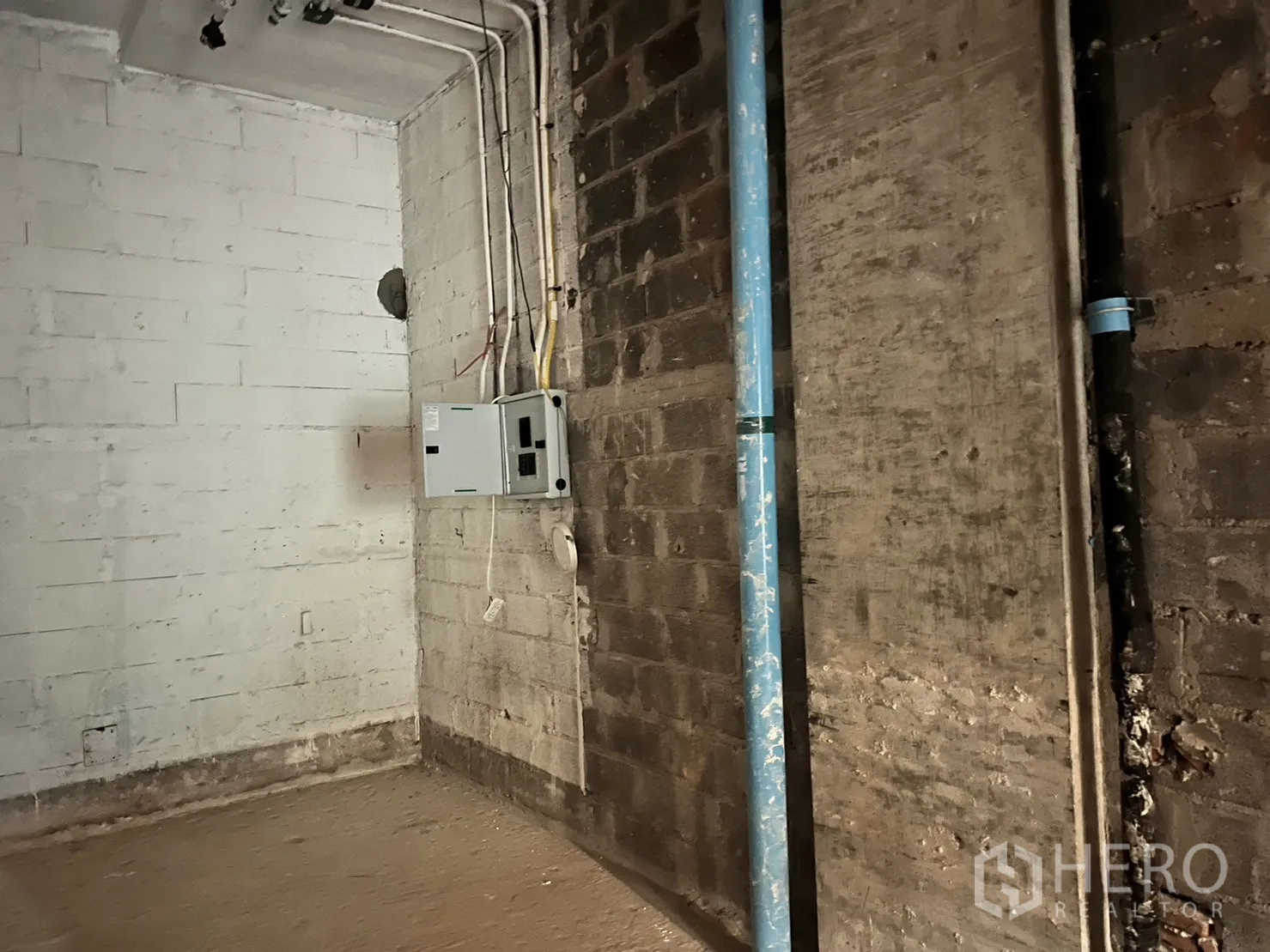 零售空间 出租在Khlong Toei, Bangkok - 店内角落的电箱、线槽与蓝色给水管，墙体为砌块墙
