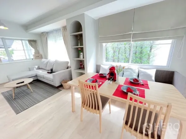 联排别墅 出租在Prawet, Bangkok - 明亮的开放式客餐厅，L形沙发、浅色木地板与大窗户，位于曼谷Prawet联排别墅。