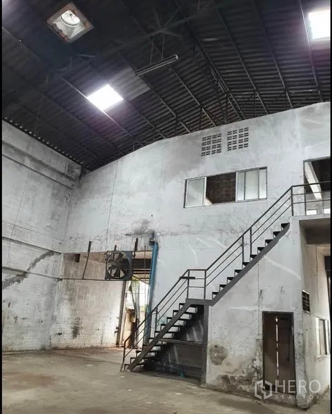 Warehouse for rent in Phra Samut Chedi, Samut Prakan - Close view of mezzanine office, large ventilation fan and metal stairs inside the warehouse.