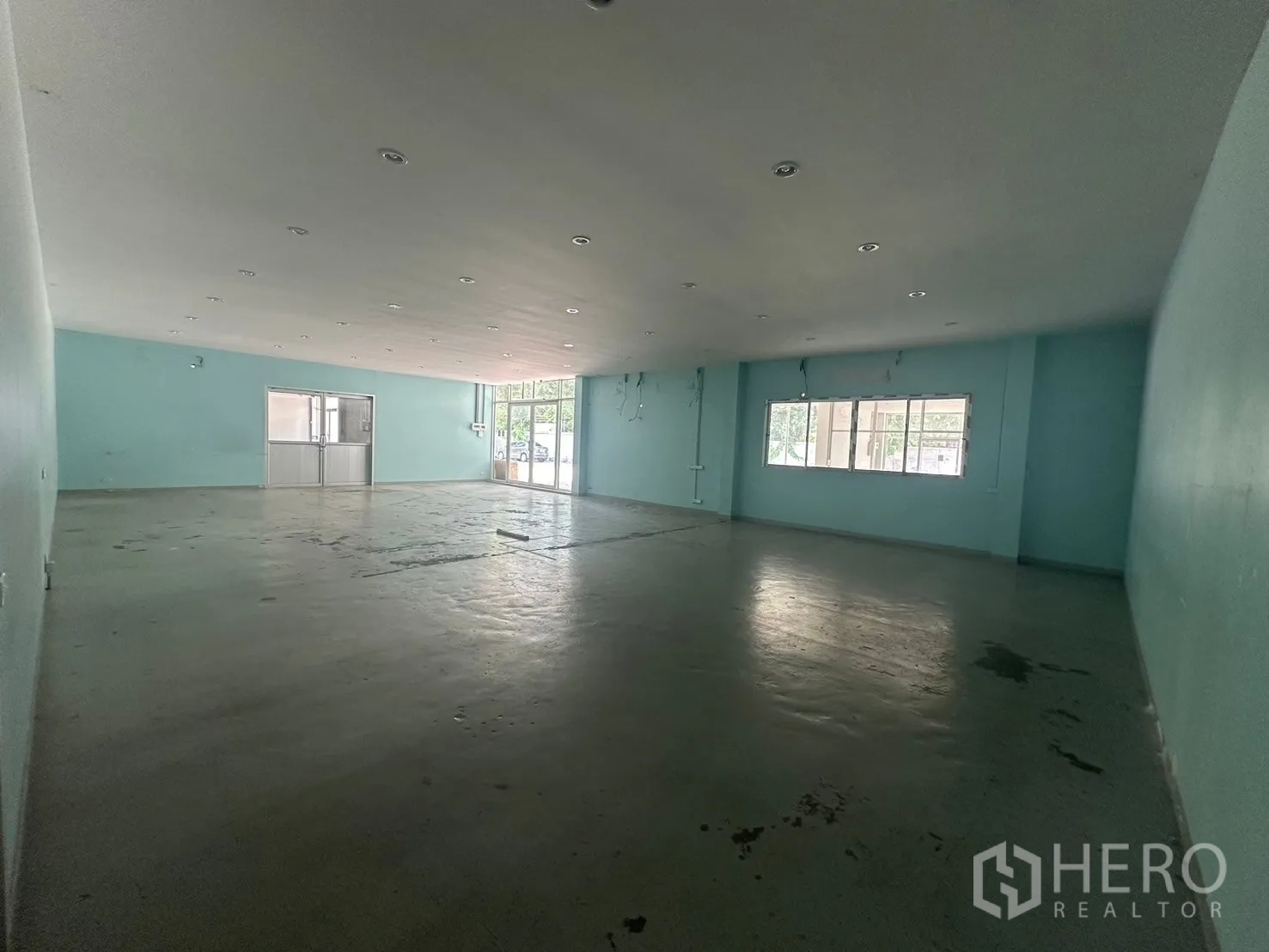 Warehouse for rent in Din Daeng, Bangkok - Open-plan office area with teal feature walls and a side window.