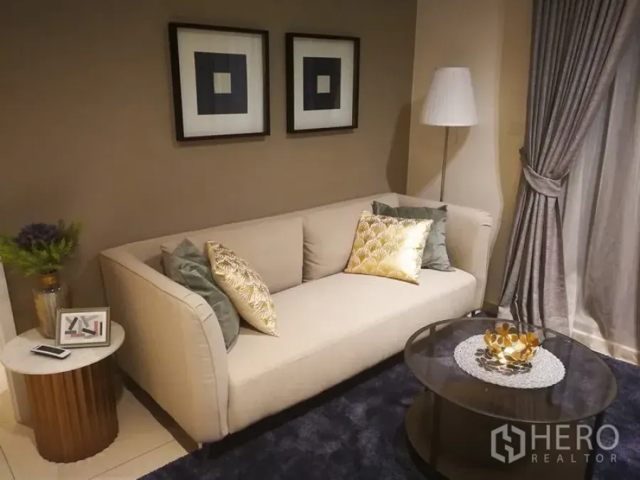 คอนโด ให้เช่าหรือขายในWatthana, Bangkok - อีกมุมของห้องนั่งเล่น โซฟา หมอนลาย งานศิลป์กรอบ และโต๊ะกลางทรงกลม