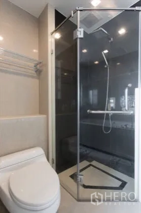 Condominium for rent in Ratchathewi, Bangkok - Modern bathroom with glass-enclosed shower, rain showerhead and toilet.