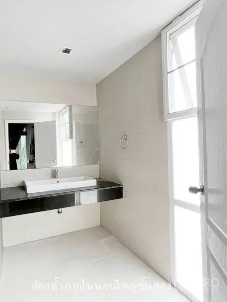 Townhouse for rent or sale in Don Mueang, Bangkok - Bright bathroom with a large mirror, window and a black countertop basin.
