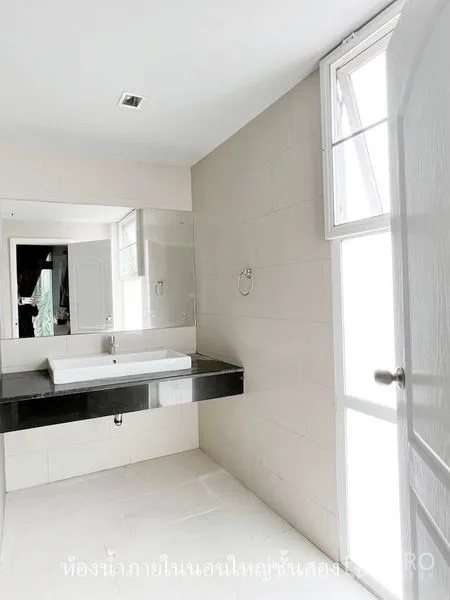 Townhouse for rent or sale in Don Mueang, Bangkok - Bright bathroom with a large mirror, window and a black countertop basin.