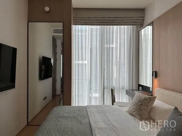 公寓 出租在Pathum Wan, Bangkok - 卧室设落地纱帘、墙挂电视与梳妆台与镜面，采光充足。