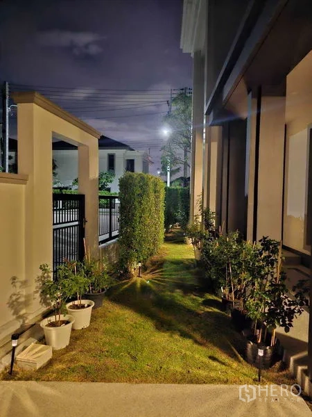 Detached House for rent in Mueang Pathum Thani, Pathum Thani - Front side garden at night with hedges, lawn and pathway lights